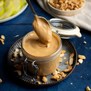 Spooning homemade cashew butter into a jar.