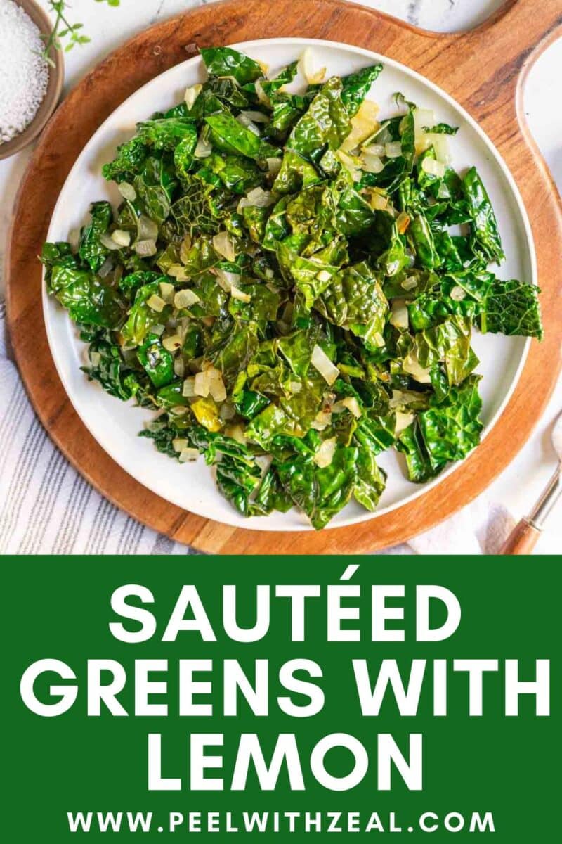 A plate of sauteed greens with chopped onions, garnished with lemon, sits on a round wooden board.