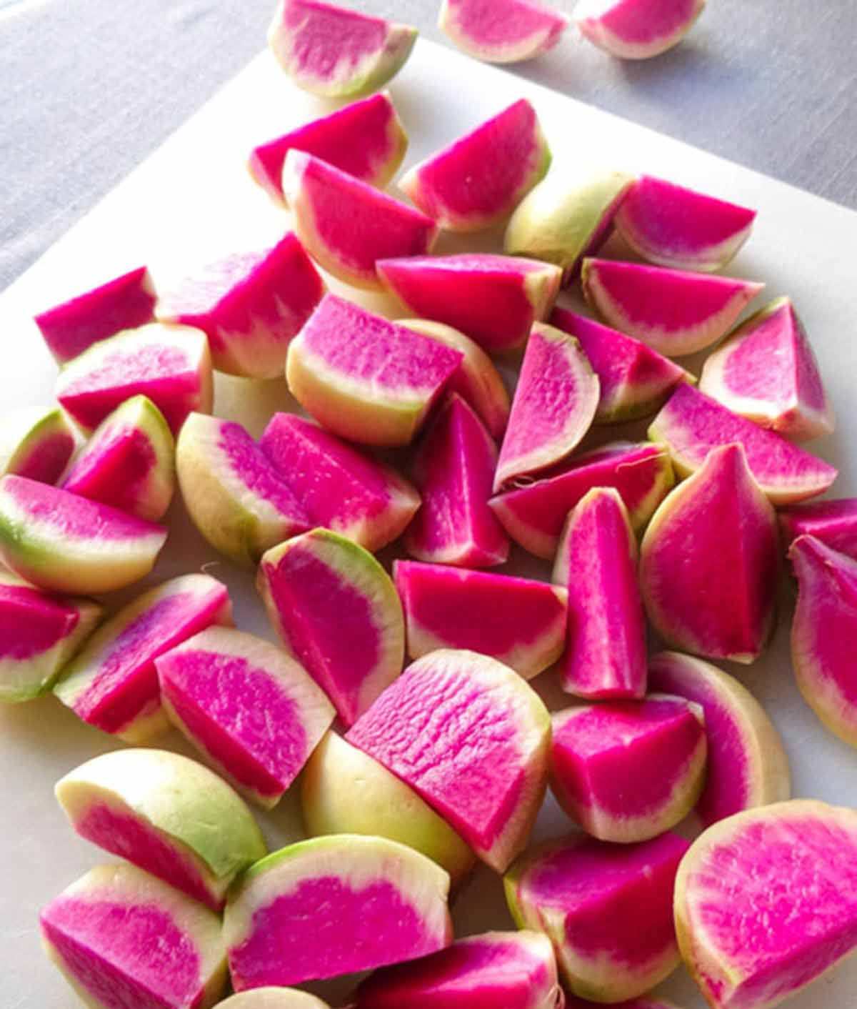 Raw watermelon radishes on cutting board.