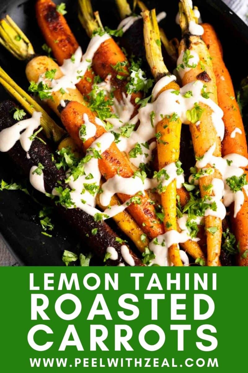 Colorful roasted rainbow carrots drizzled with lemon tahini sauce and garnished with herbs on a sleek black platter.