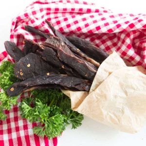 chili lime beef jerky wrapped in paper on a plaid napkin