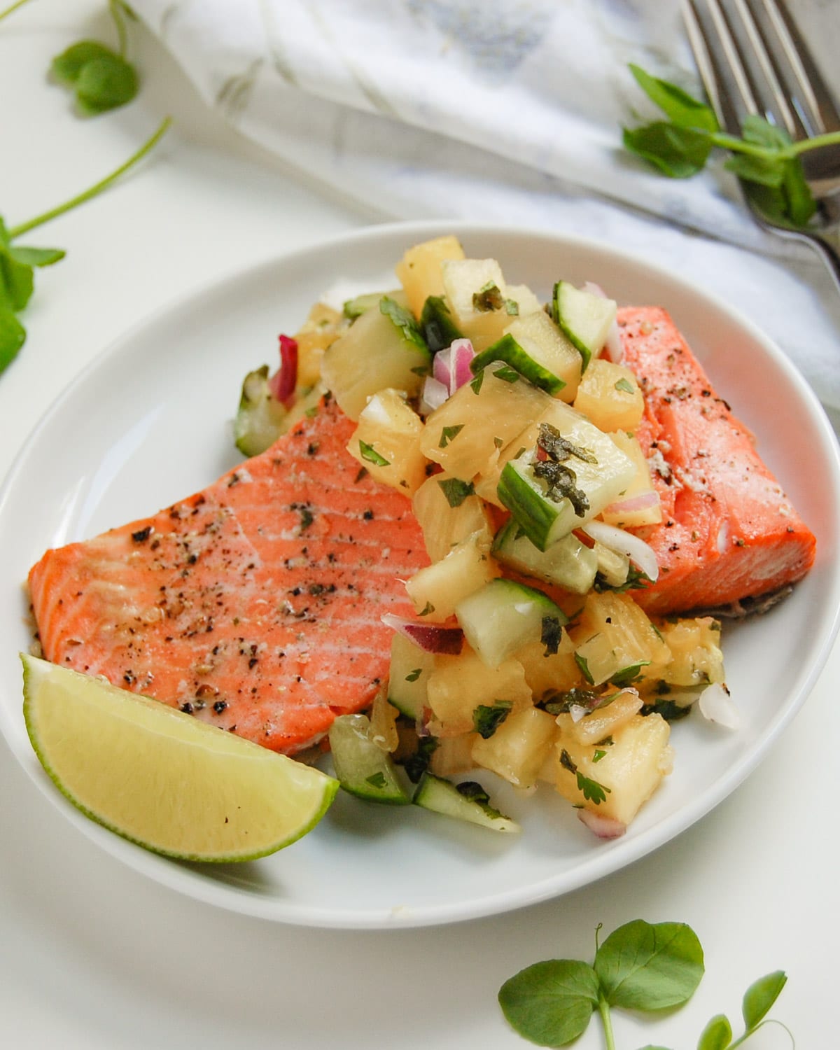 roasted salmon filet with pineapple salsa on white plate