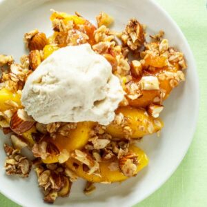 close up of peach crisp on a plate with ice cream
