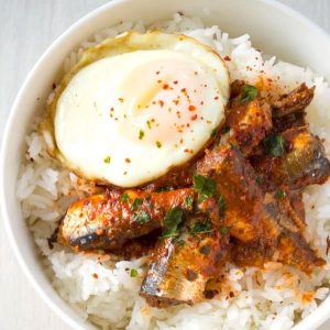 egg, sardines in tomato sauce on rice in white bowl