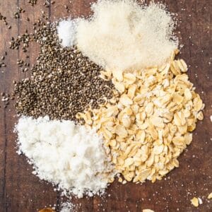 A collection of dry ingredients on a wooden surface, including chia seeds, flour, oats, sugar, and salt arranged in separate sections—perfect for whipping up instant overnight oats.