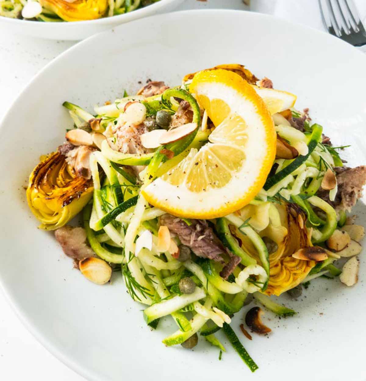 Zucchini noodles in a bowl with lemon.