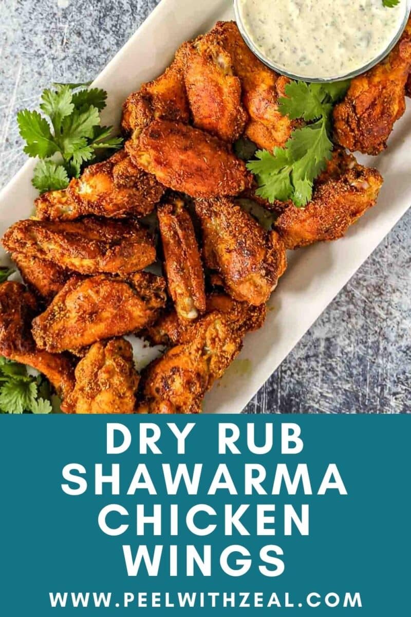 Shawarma-spiced chicken wings are artfully arranged on a platter, garnished with vibrant cilantro, and paired with a flavorful dipping sauce.