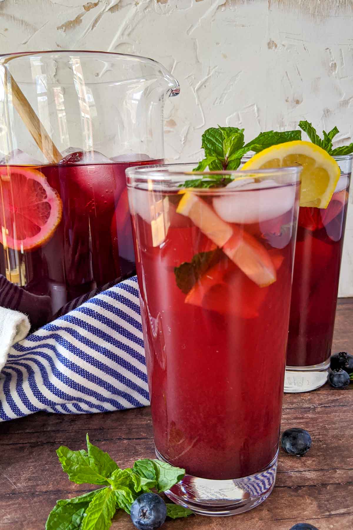 blueberry tea in glass with pitcher behind