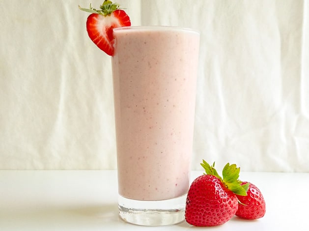 strawberry tahini milkshake in a glass with extra strawberries