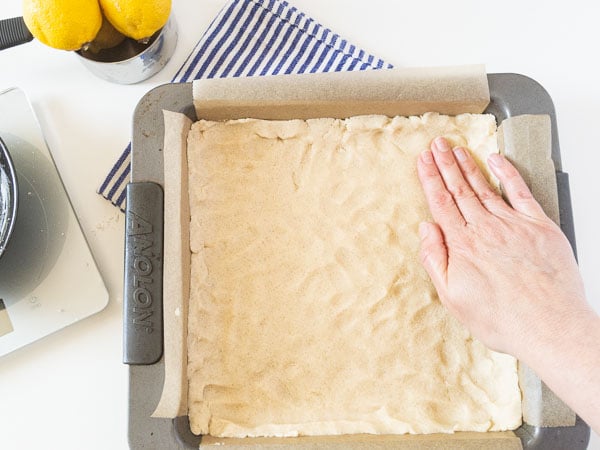 hand pressing dough into baking pan