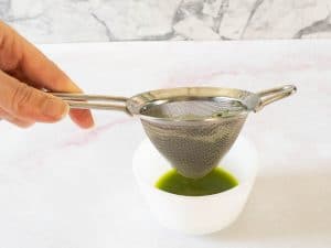 straining basil oil into a jar