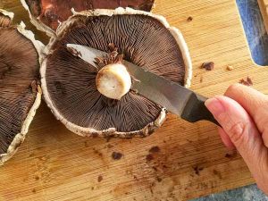 using a paring knife to remove portobello mushroom stem