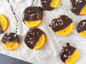 oranges dipped in chocolate resting on parchment