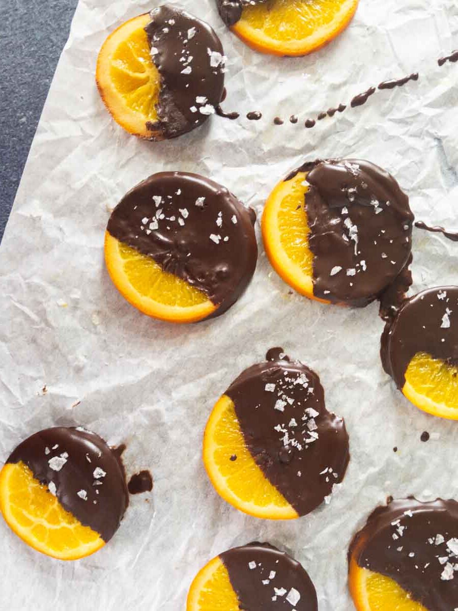 oranges dipped in chocolate resting on parchment