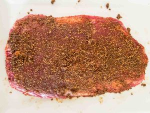 flank steak with seasoning before grilling