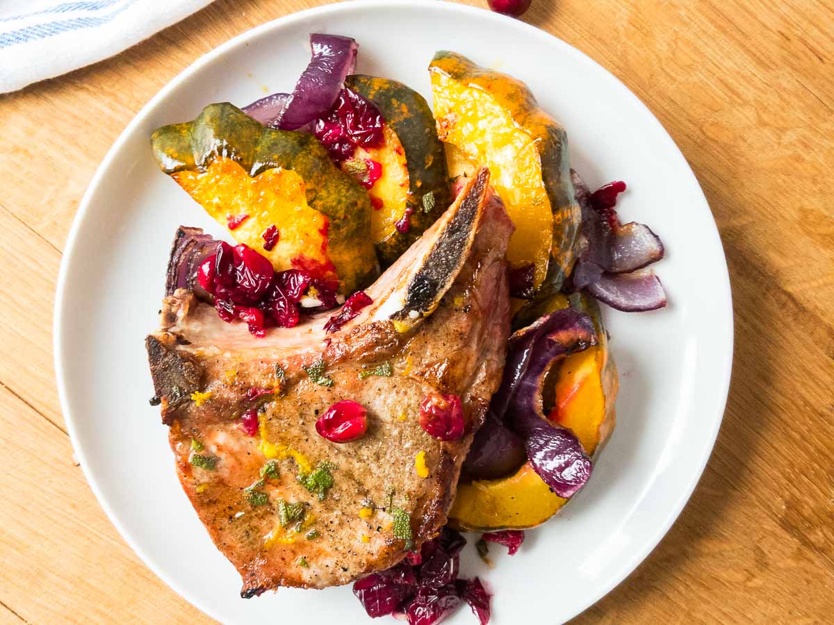 Pork chops and acorn squash on a dinner plate.