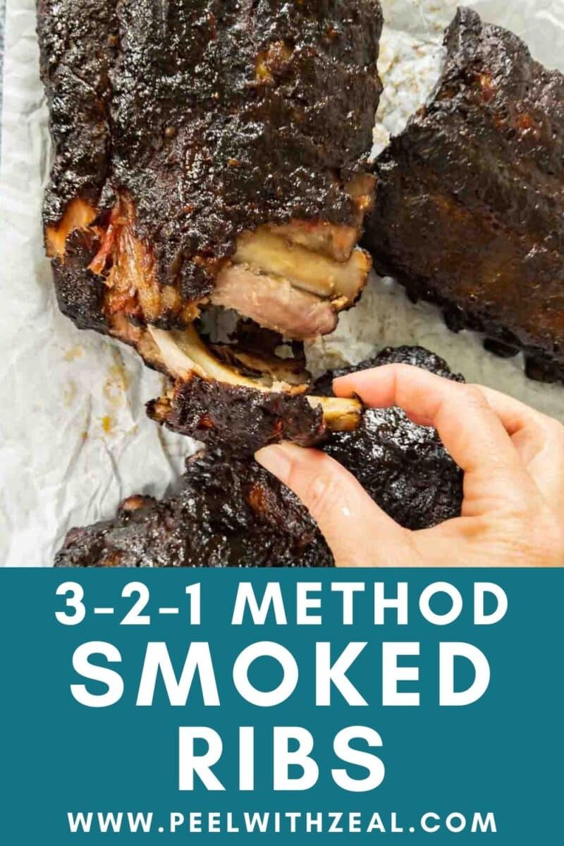 A hand holding smoky, tender smoked baby back ribs with a dark, glazed exterior on parchment paper. Text reads "3-2-1 Method Smoked Ribs" and "peelwithzeal.com" at the bottom.