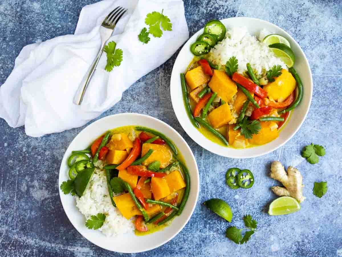Thai green curry with colorful vegetables served of rice in two bowls.
