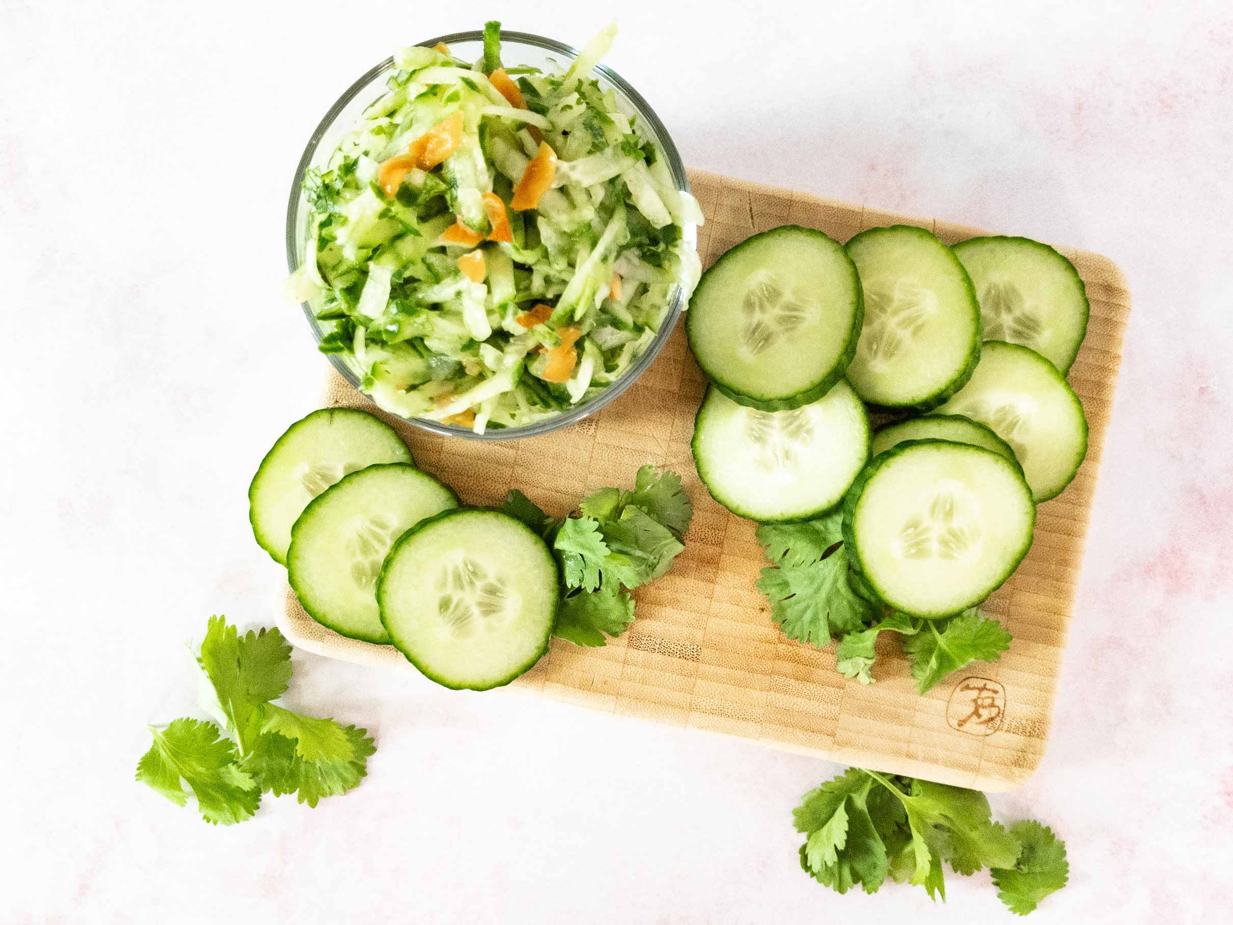 Chutney in bowl on cutting board with cucumbers.