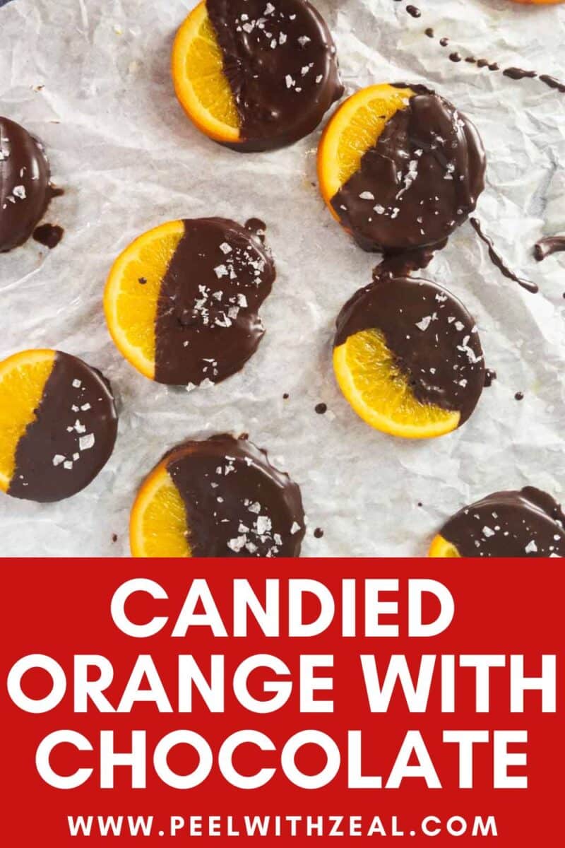 Candied orange slices dipped in dark chocolate and sprinkled with sea salt rest on parchment paper