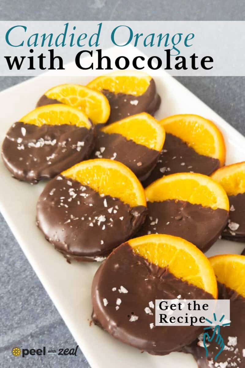 Candied orange slices partially dipped in chocolate and arranged on a white rectangular plate.