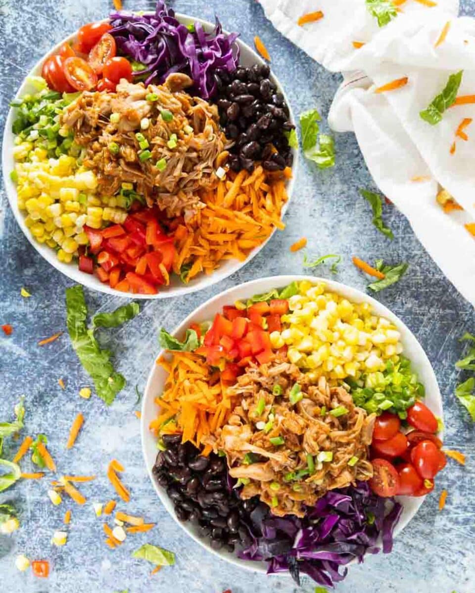 Two colorful salads in bowls on a counter.