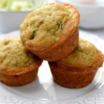 three zucchini muffins stacked on a plate