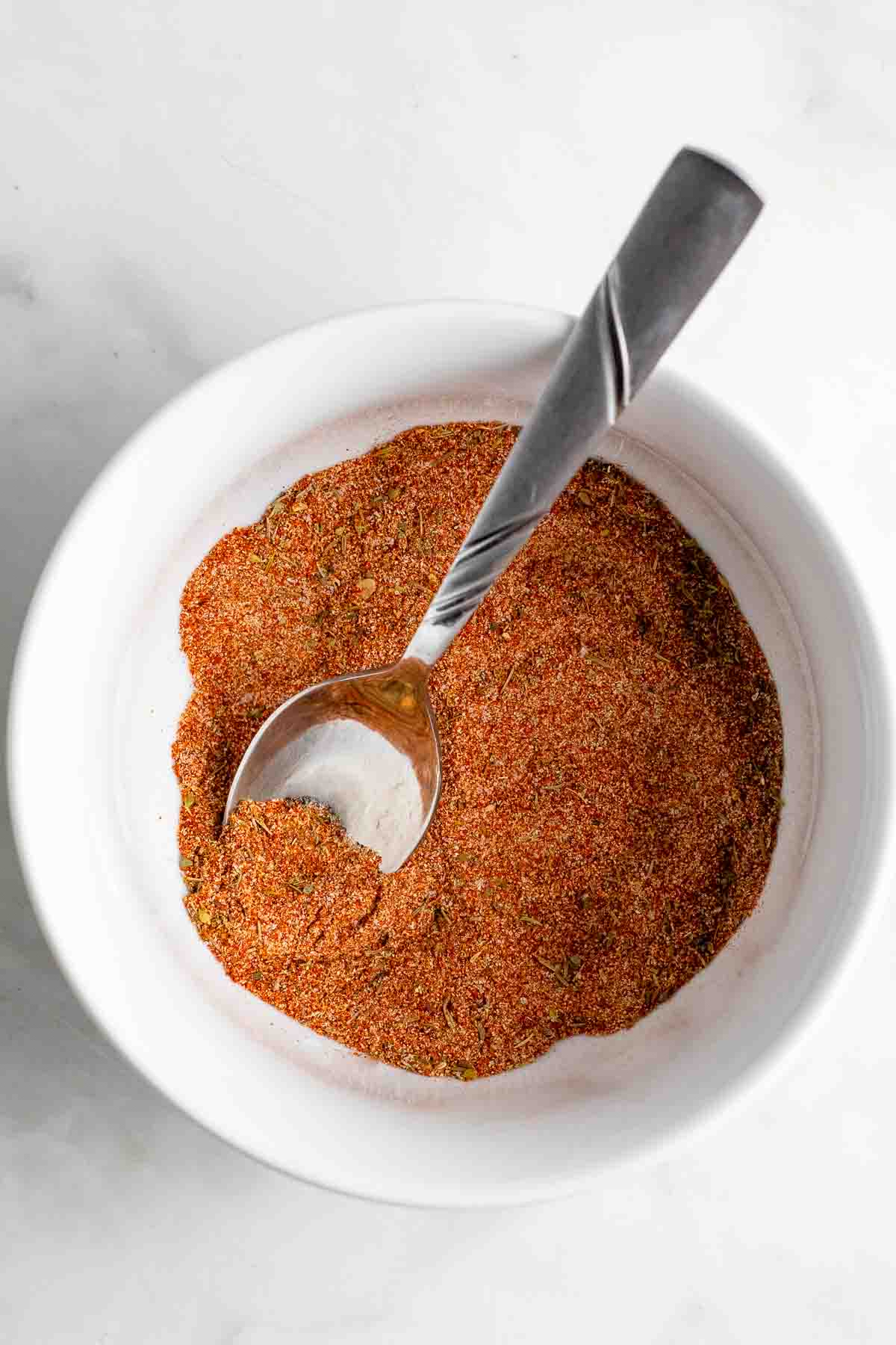 Blackened seasoning Cajun dry rub in a white bowl with silver spoon.