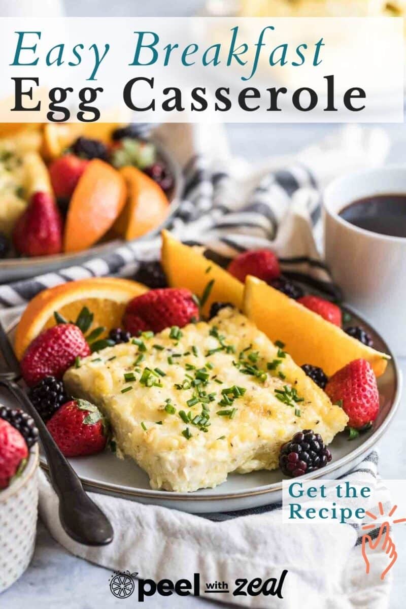 Plate of breakfast casserole garnished with chives, served with mixed berries and orange slices. Coffee cup and another plate in the background. Text reads: "Easy Breakfast Egg Casserole.