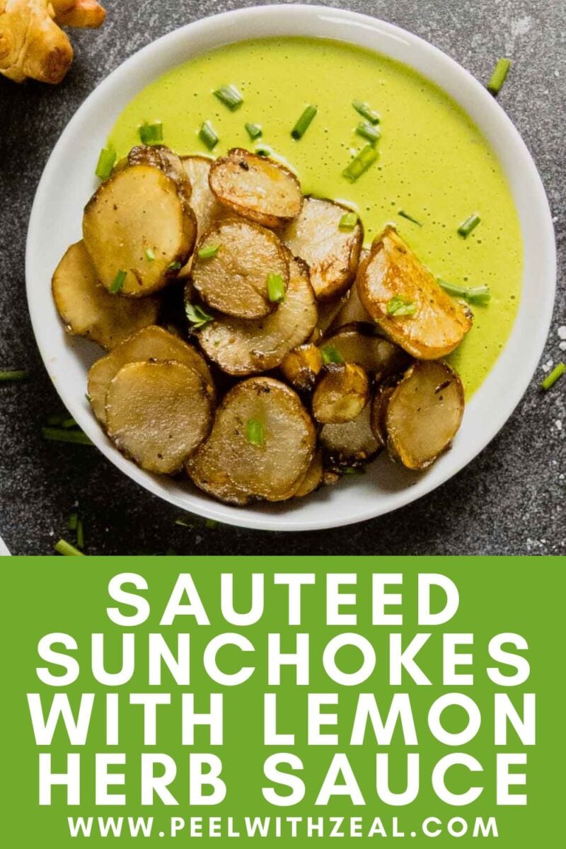 A plate of sauteed sunchokes served with green lemon herb sauce, garnished with chopped herbs, is beautifully presented on a dark surface.