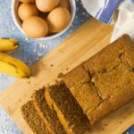 oat flour banana bread on cutting board with eggs and bananas