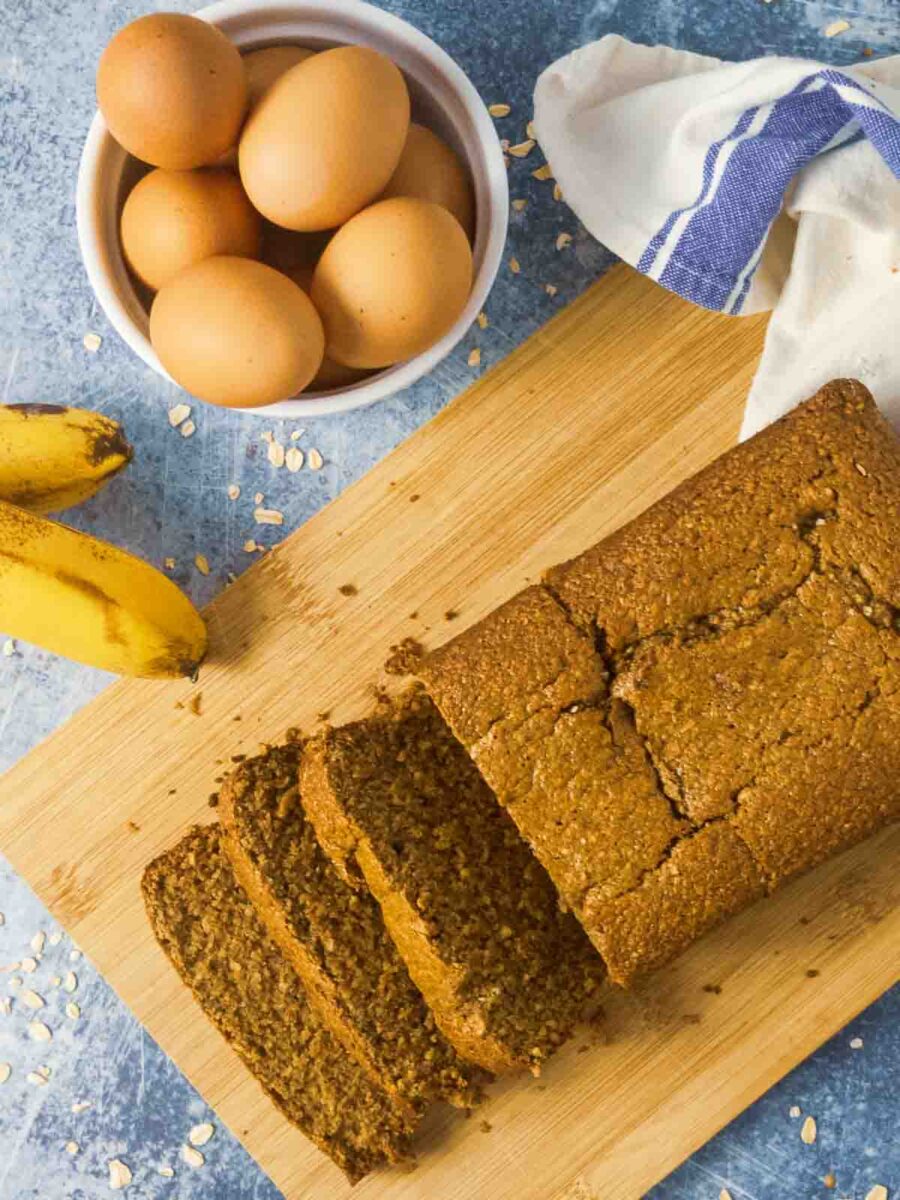 oat flour banana bread on cutting board with eggs and bananas