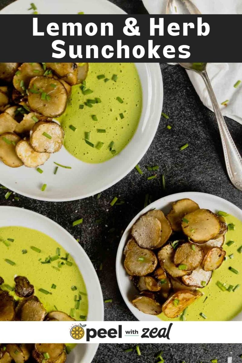 Two white bowls containing sauteed sunchokes and a green lemon herb sauce, garnished with chopped chives, with a spoon and napkin on the side.