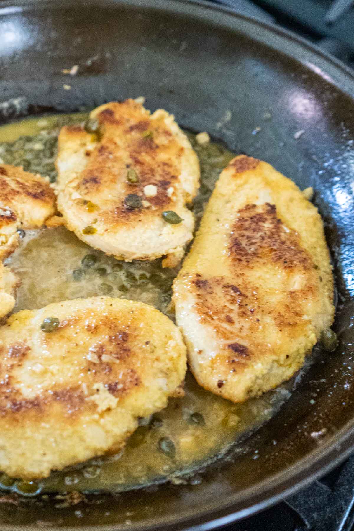 Cooking chicken in piccata sauce.