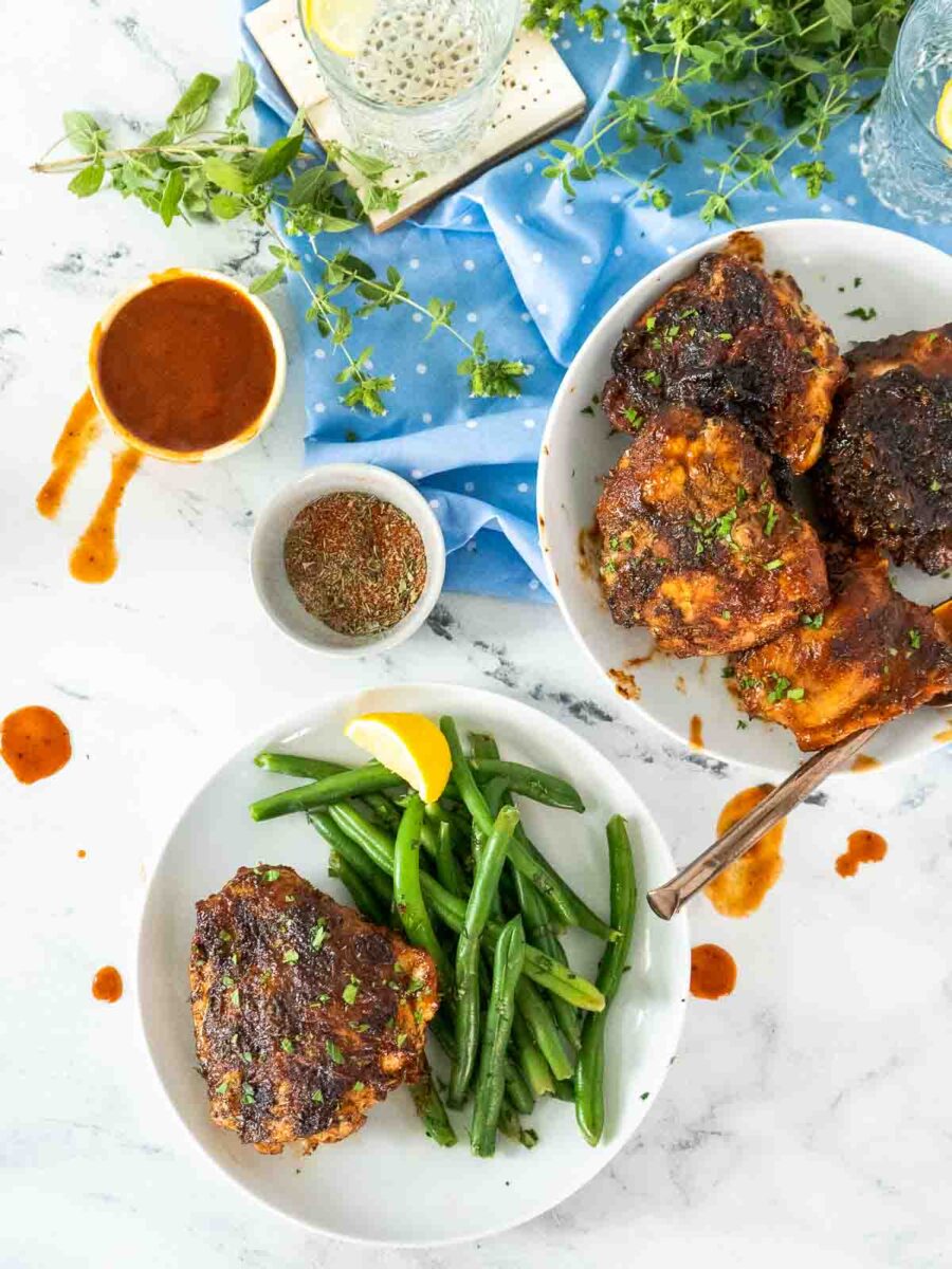 BBQ chicken on serving plate and one plate with chicken and green beans