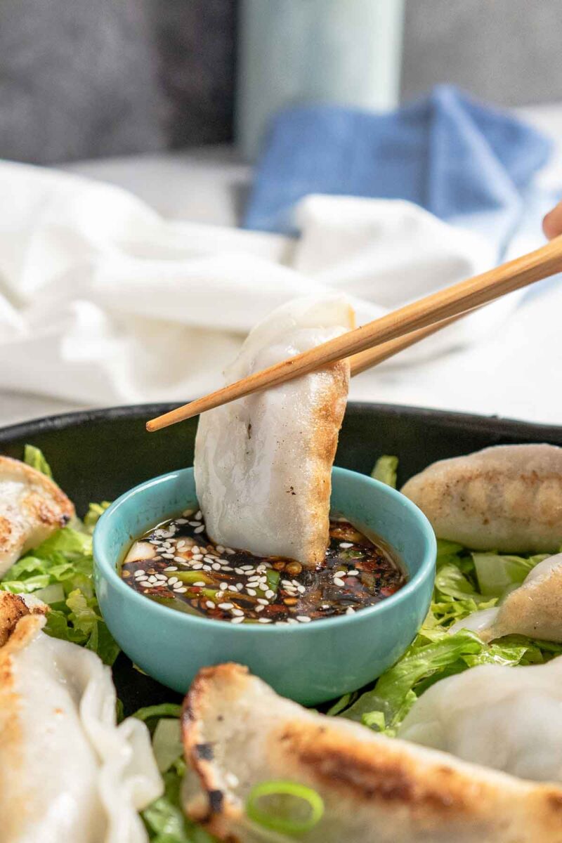 dunking a potsticker into gyoza sauce