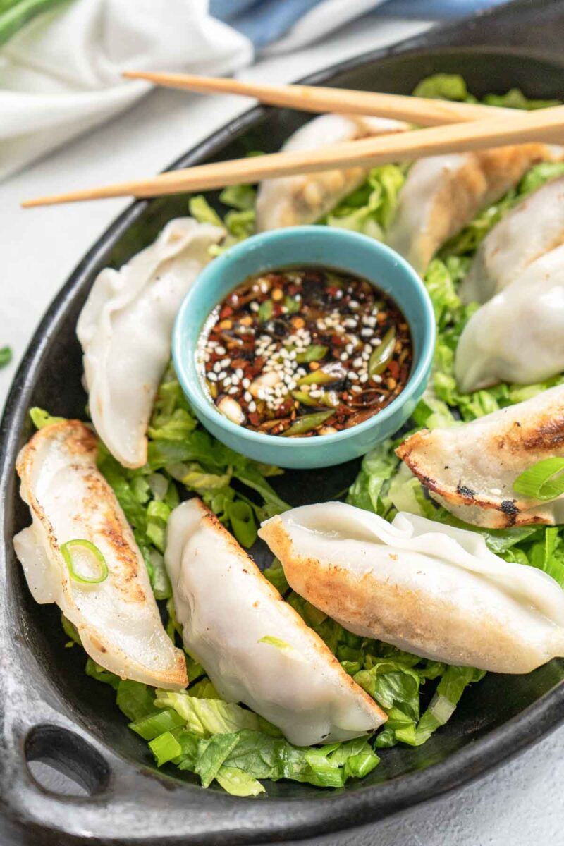 plate of dumplings with a bowl gyoza sauce and chopsticks