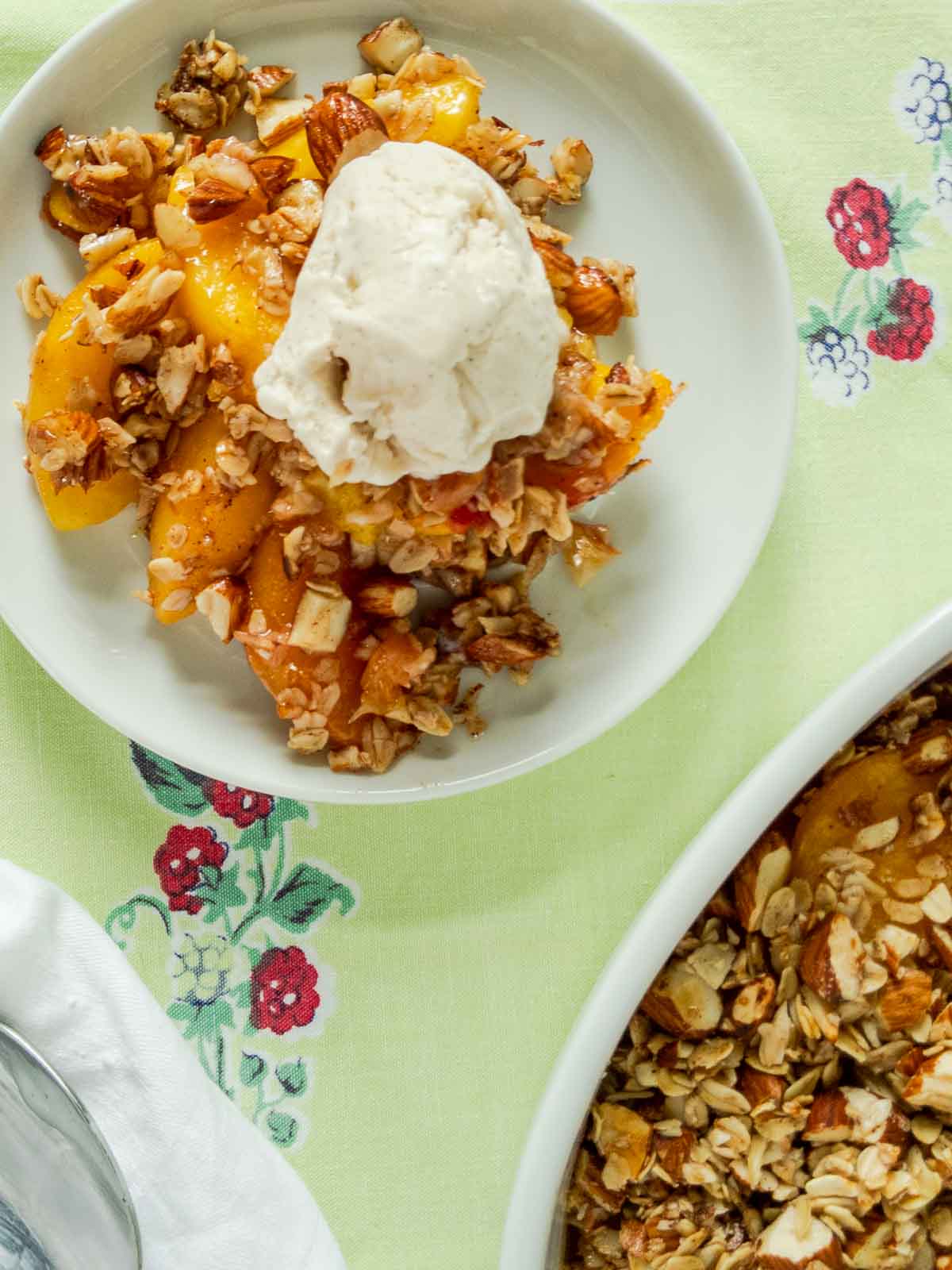 serving of peach crisp with a scoop of ice cream on a white plate