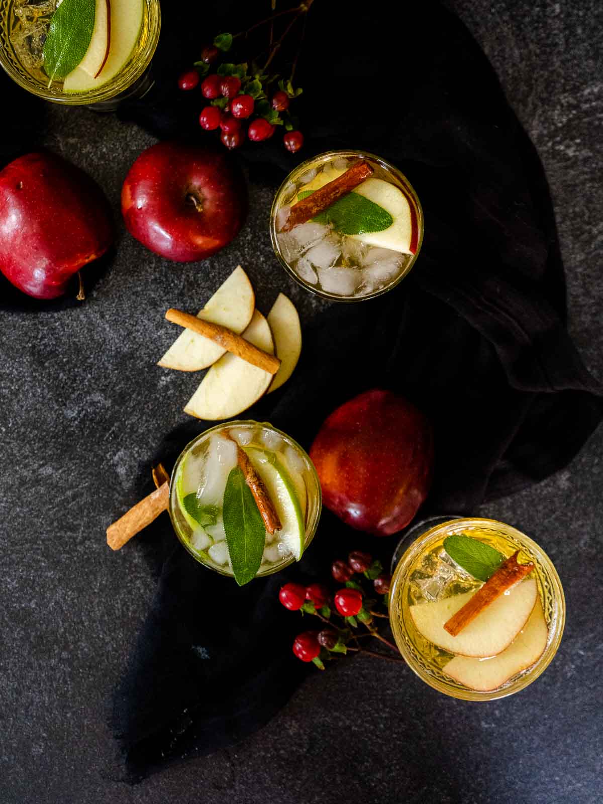 apples and cinnamon sticks with whiskey cocktail on black background