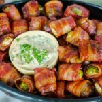 bacon wrapped brussels sprouts in bowl with a dipping sauce.