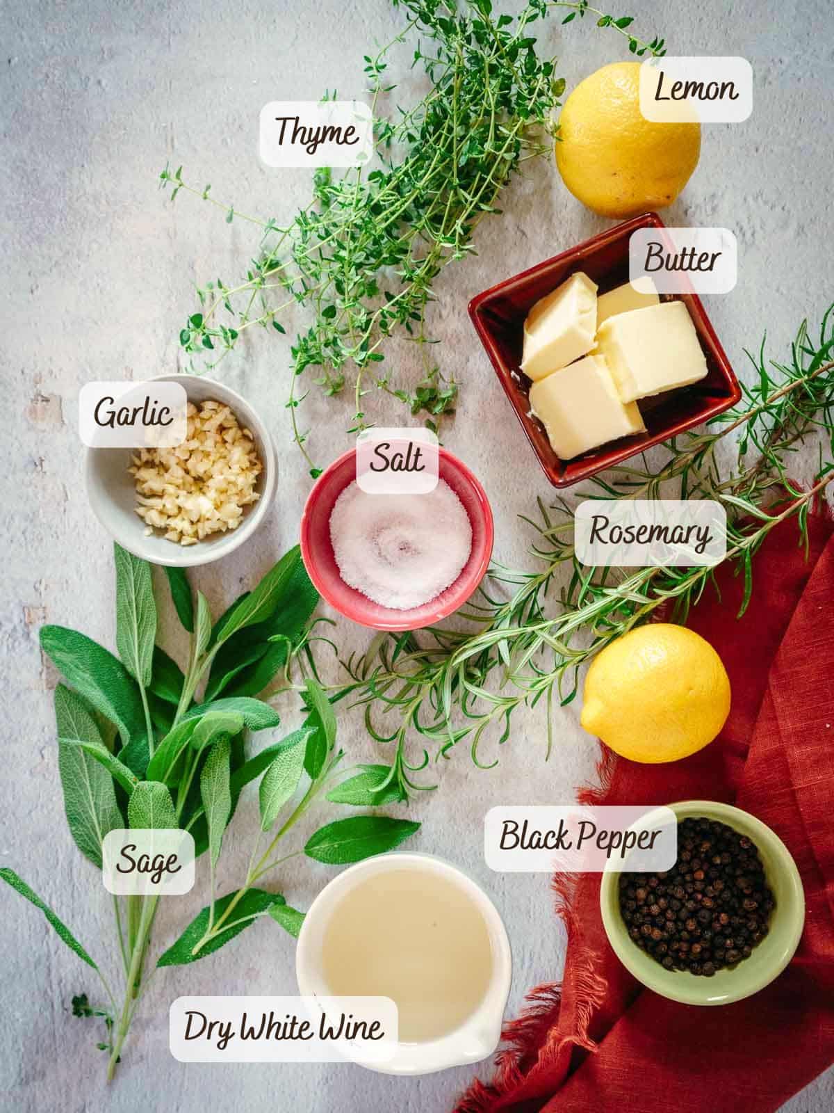 Flat lay of ingredients for roasting a bone in turkey breast, including thyme, lemon, butter, garlic, salt, rosemary, sage, black pepper, and a cup of dry white wine, all labeled.