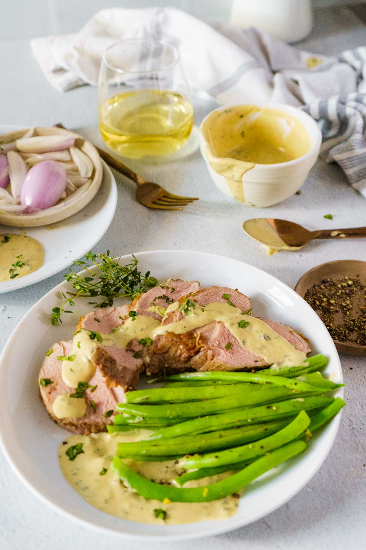 sous vide pork tenderloin with green beans and a mustard sauce on a dinner plate