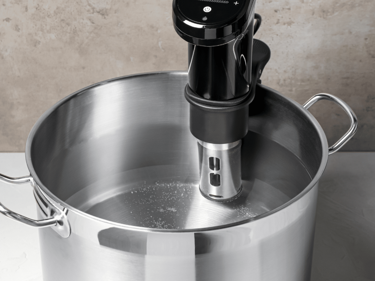 Sous vide immersion circulator in a stainless steel pot filled with water, perfect for preparing sous vide asparagus to perfection.