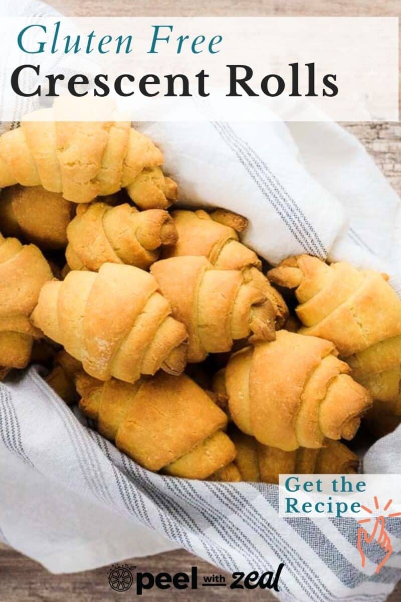 A basket filled with warm, gluten free crescent rolls wrapped in a striped cloth. Text on the image reads "Gluten Free Crescent Rolls" with a button saying "Get the Recipe".
