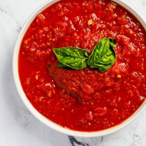 San marzano tomato sauce in a bowl with two basil leaves.