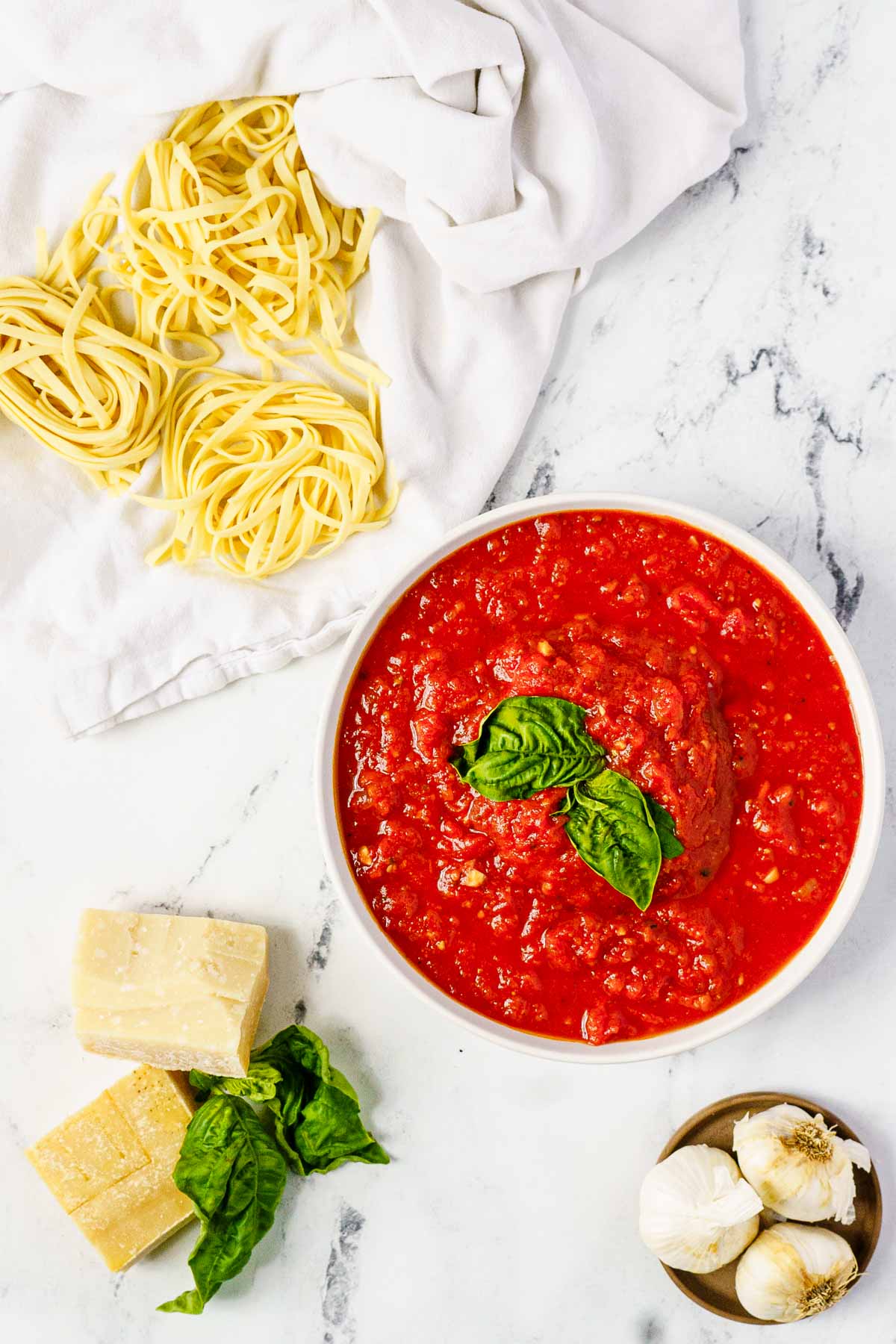 sauce in bowl with fresh pasta and parm on counter