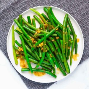 curried green beans on a plate on a grey cloth