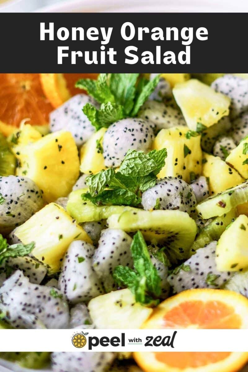 This Dragon Fruit Salad features pineapple, orange slices, and fresh mint leaves. Labeled "Honey Orange Fruit Salad," it's a refreshing mix of vibrant flavors.