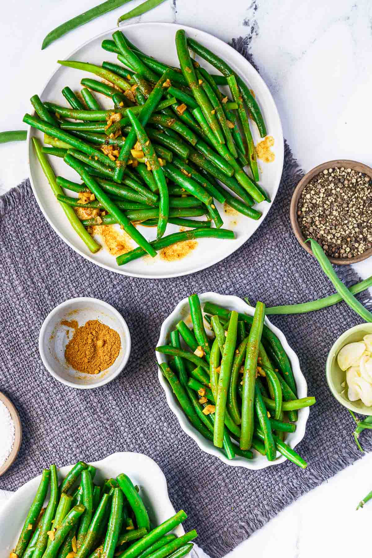 curried green beans on plates with spices in bowls