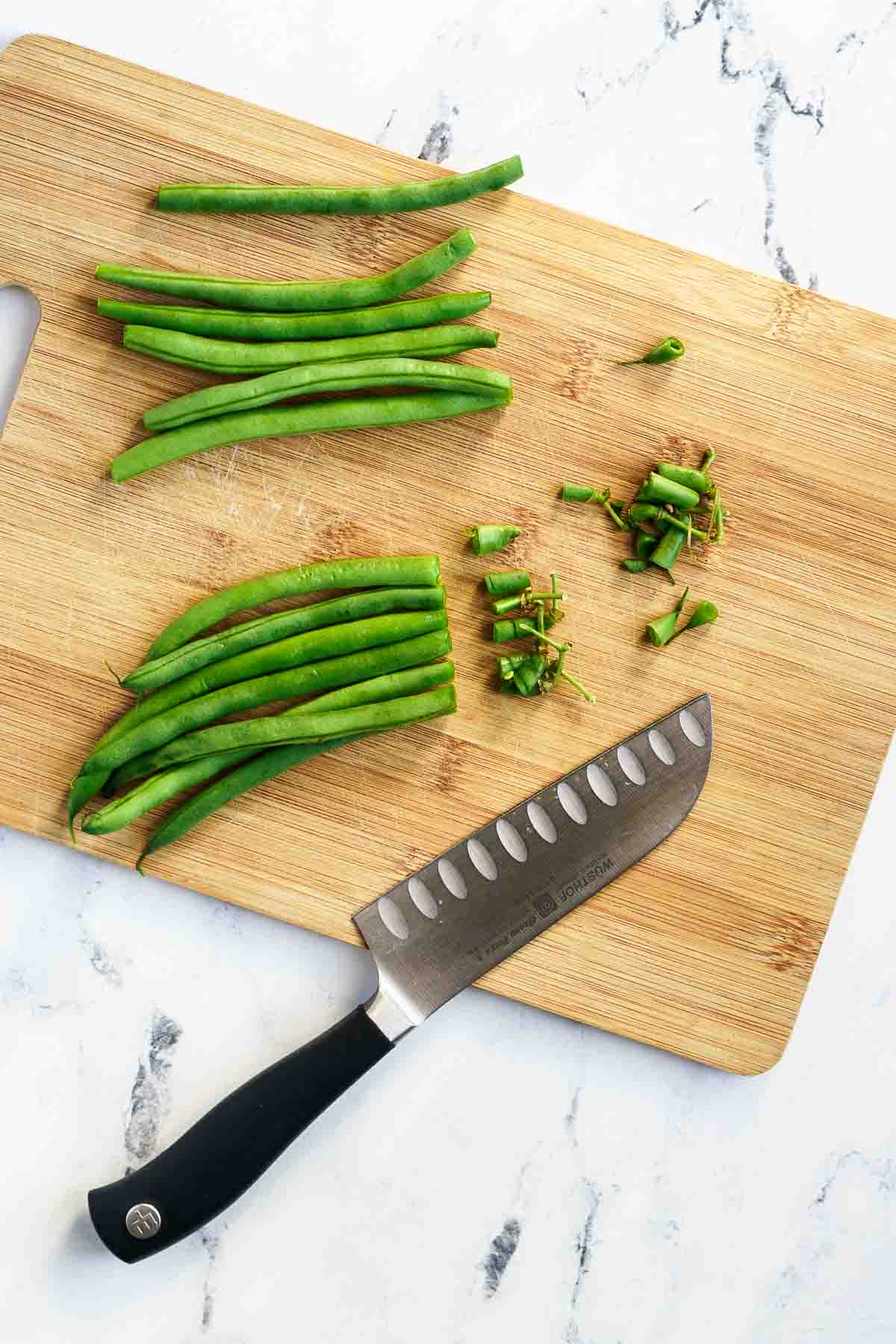 cutting board with fresh green beans with ends trimmed off
